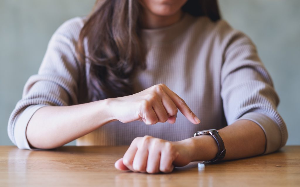 Closeup of a woman pointing finger at a wristwatch while waiting for someone